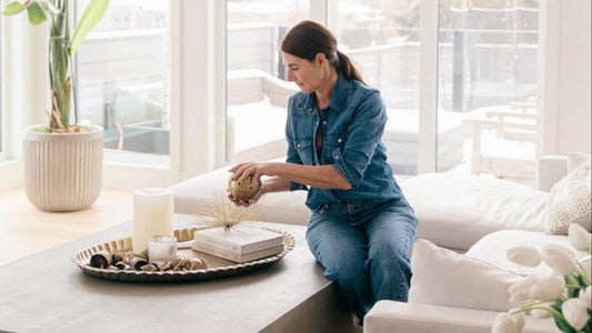 Woman sitting on coffee table in living room organizing certerpiece