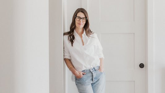 Woman standing and leaning against a wall in a sparse room