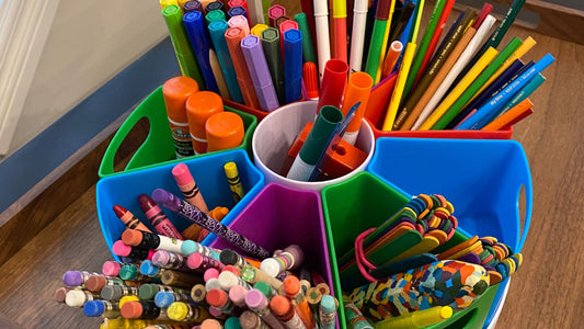 An assortment of pens, pencils, markers and crayons in a desk carousel