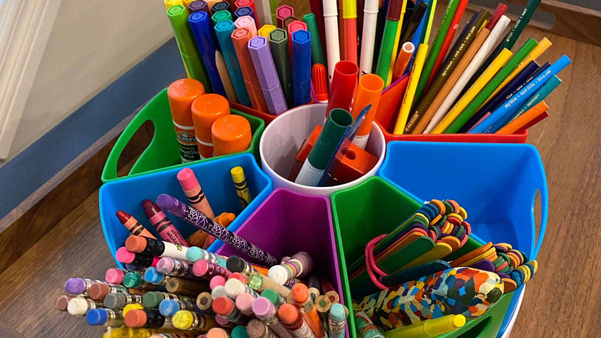An assortment of pens, pencils, markers and crayons in a desk carousel